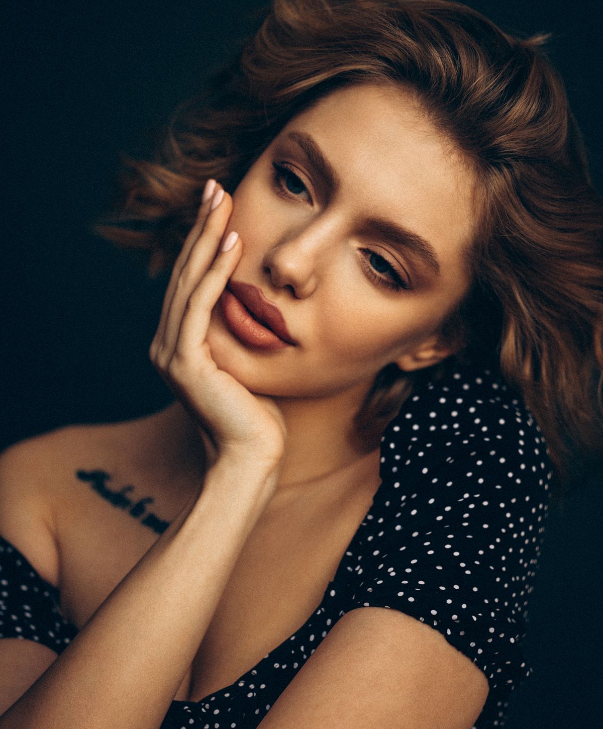 Woman with soft curls, hand on face.