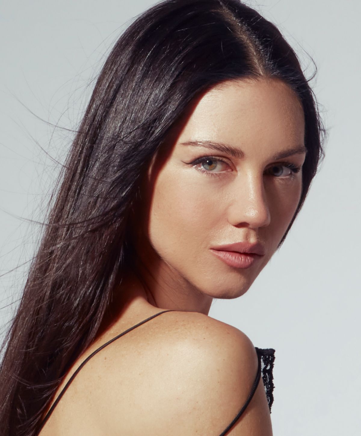 Woman with long hair, looking over her shoulder.